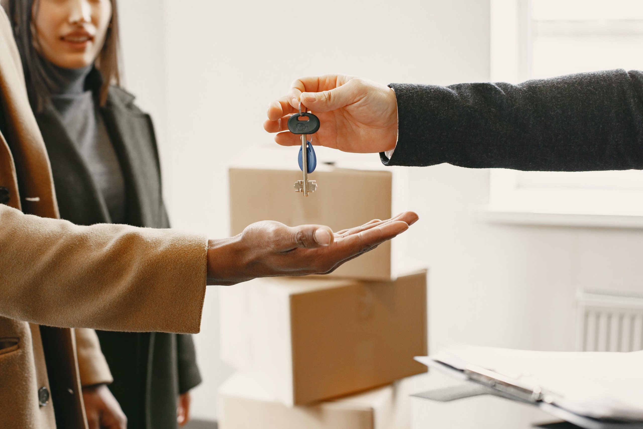 Hands exchanging house keys over moving boxes, representing the South Jersey home buying process.